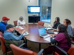 colleagues around a table, speaking to one another