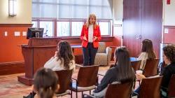 Valeria Aloe in a red blazer, speaking to a seated audience.