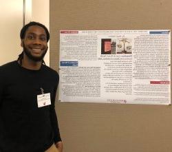 A man smiles in front of his research poster.